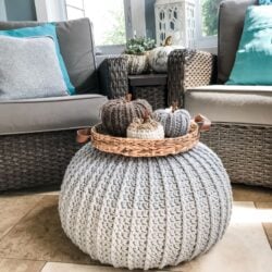 A gray crocheted ottoman with pumpkins on it, perfect for a DIY floor pouf tutorial.