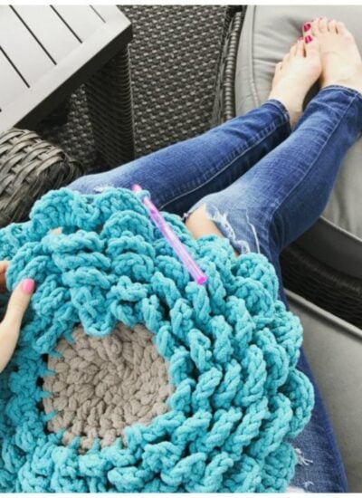 A person sitting on a couch holding a crocheted flower.