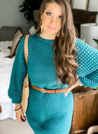 A woman wearing a teal sweater dress effortlessly styles the Piece of Cake Cardi, showcasing its versatile design and cozy comfort.