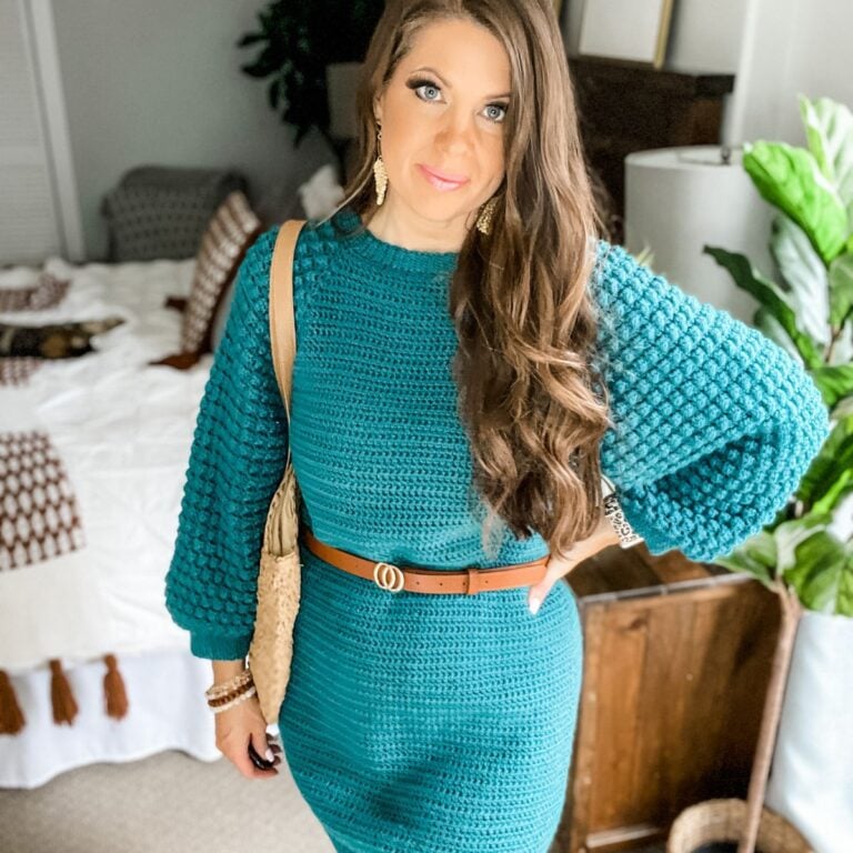 A woman wearing a teal sweater dress effortlessly styles the Piece of Cake Cardi, showcasing its versatile design and cozy comfort.
