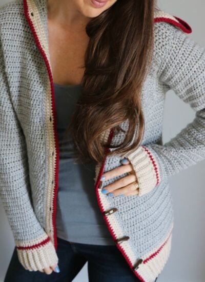 A young woman wearing the Piece of Cake Cardi, a grey and red cardigan.