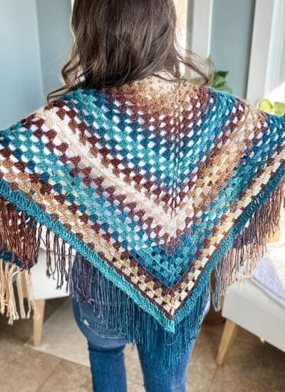 A woman wearing a crochet shawl in a living room.