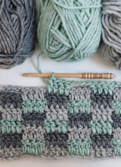 A group of crocheted yarns and knitting needles on a white surface.
