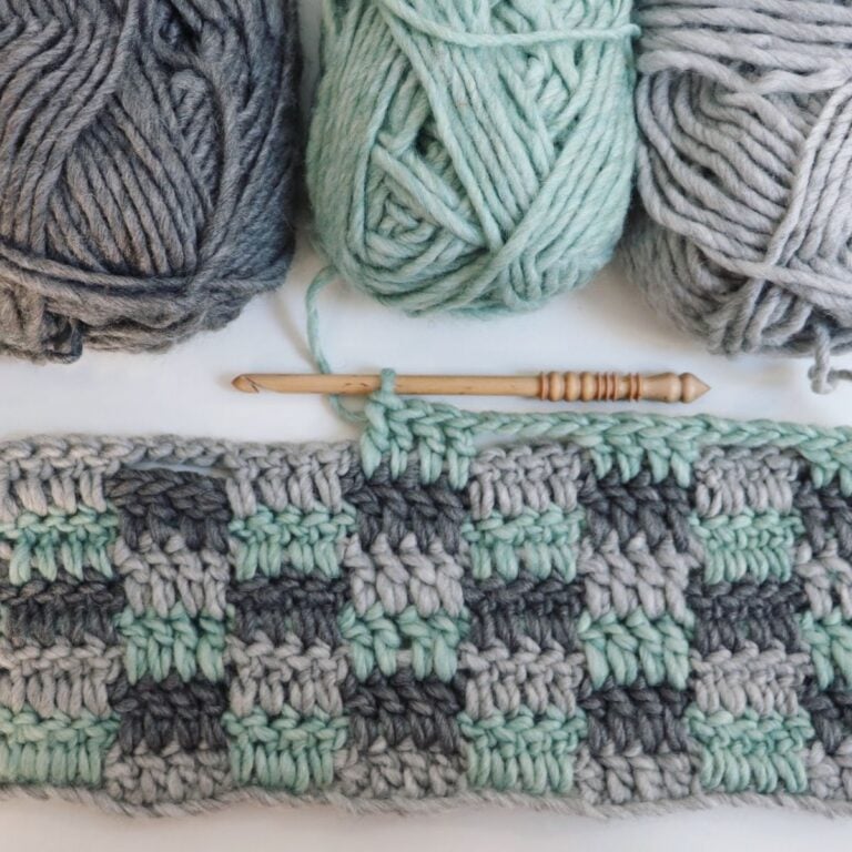 A group of crocheted yarns and knitting needles on a white surface.