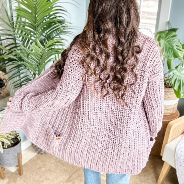 The back view of a woman wearing a cuddly pink cardigan sweater.