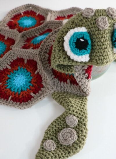 A crocheted turtle hat and mittens transformed into a Hooded Sea Turtle Blanket.