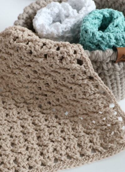 Bulky crocheted dishcloths in a basket on a table.