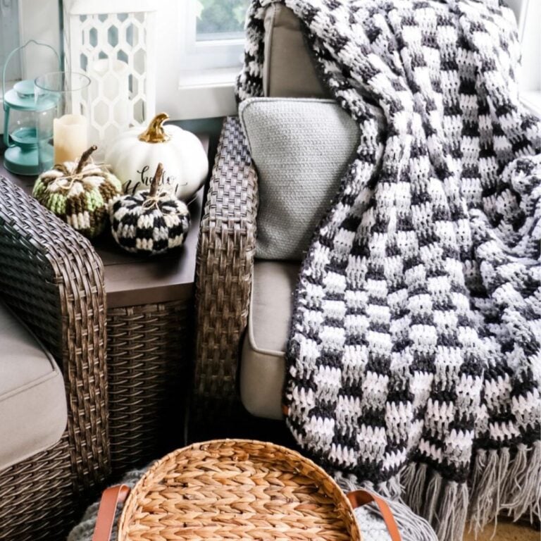 A bulky black and white blanket is sitting on a chair next to a wicker basket.