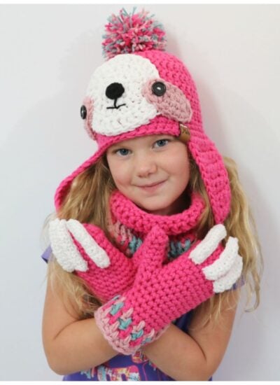 A little girl wearing a pink sloth hooded cowl.
