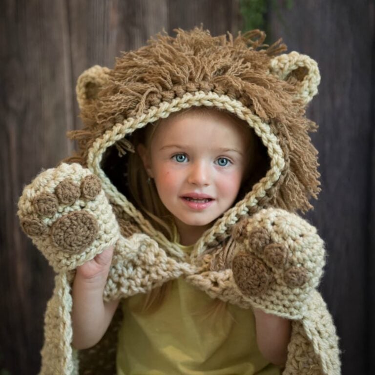 A little girl wearing a hooded lion blanket.