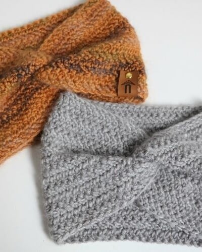 Two Herringbone Twist Ear Warmers on a white surface.