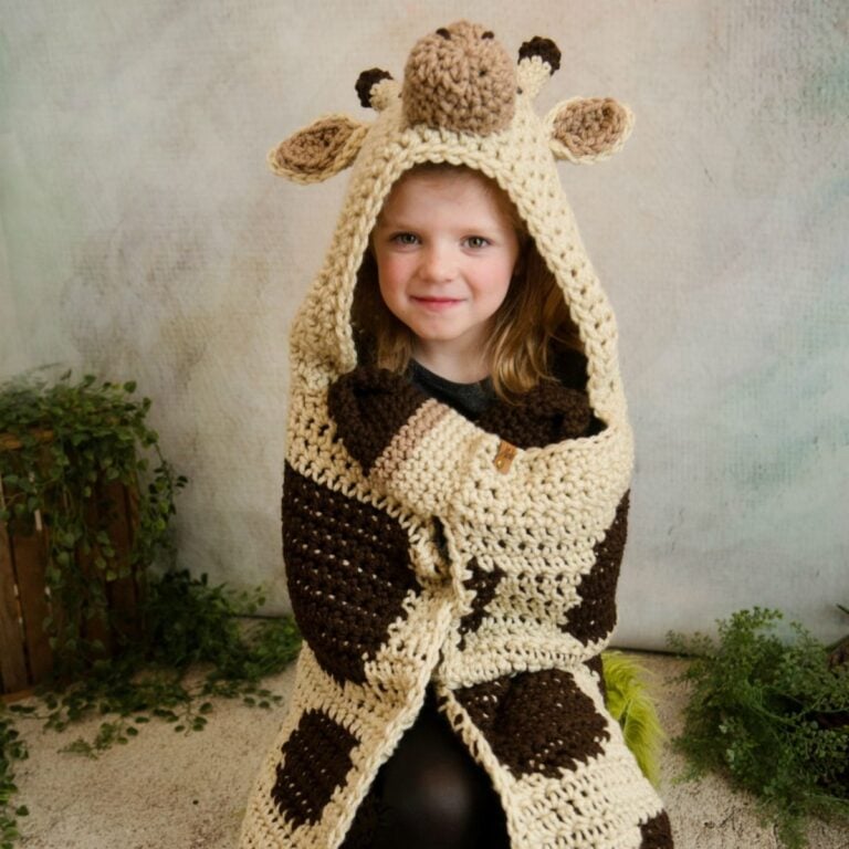 A little girl wearing a hooded giraffe blanket.