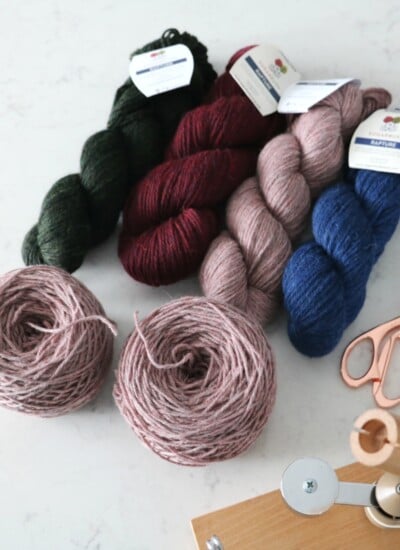 Skeins of yarn and scissors on a table, ready to turn your hanks into cakes.