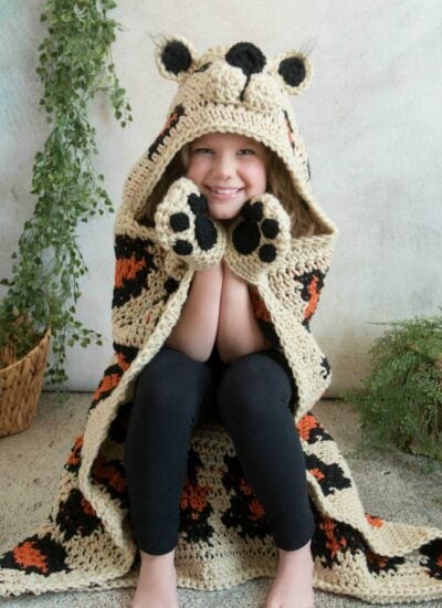 A little girl wearing a hooded blanket resembling a tiger.