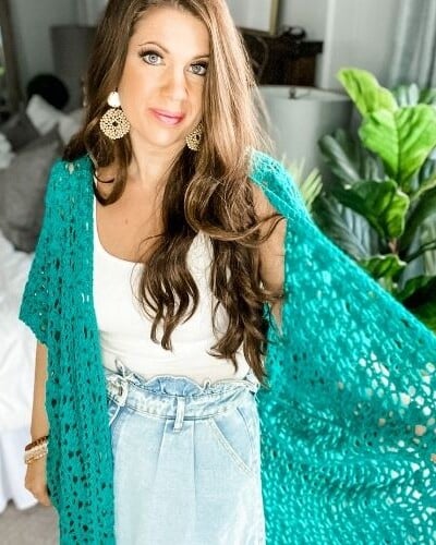 A woman wearing a turquoise Lacy Days Kimono and denim skirt.