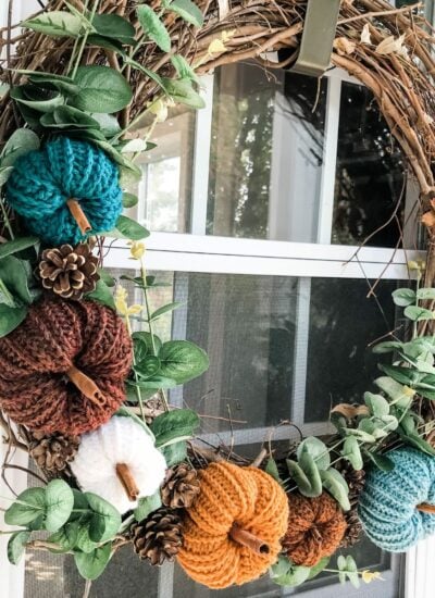 A crochet pumpkin wreath hangs on a front door.