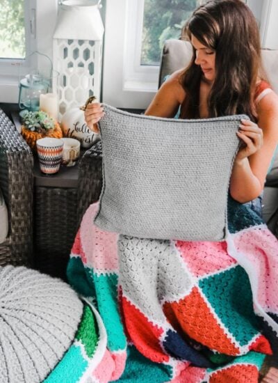 A woman is sitting in a chair holding a crocheted fall wreath.
