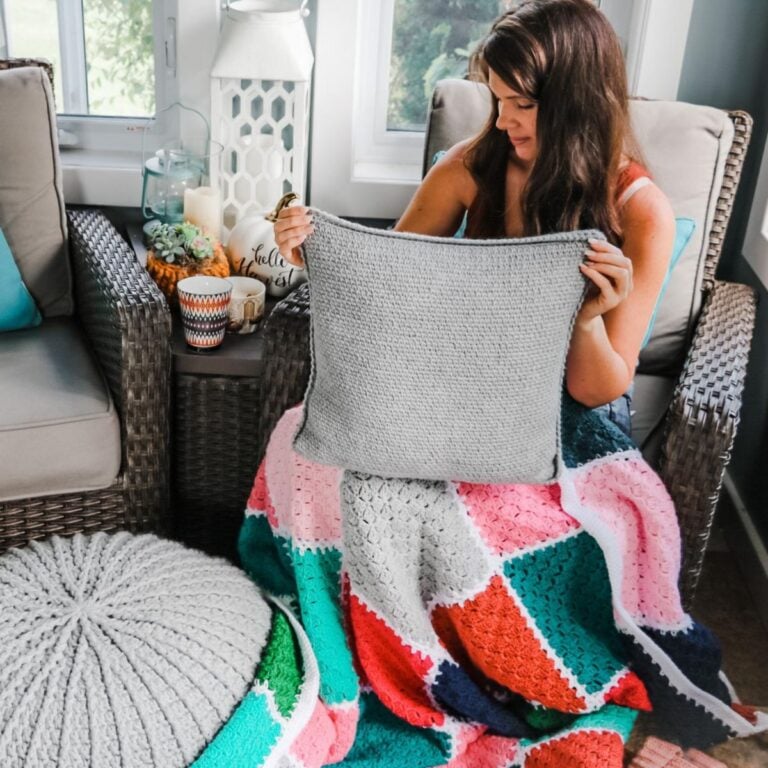 A woman is sitting in a chair holding a crocheted fall wreath.
