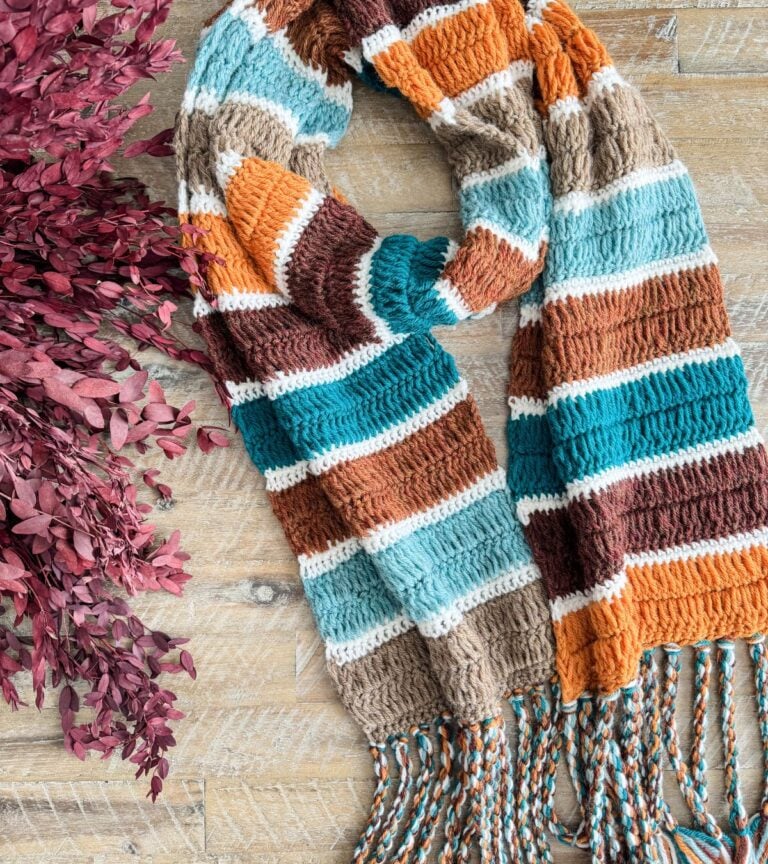 A crochet blanket scarf on a wood surface.