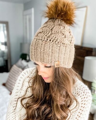A woman wearing a beanie with a crochet baby hat pattern.