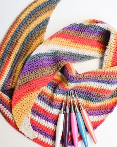 A vibrant crochet scarf, expertly crafted using a pair of knitting needles.