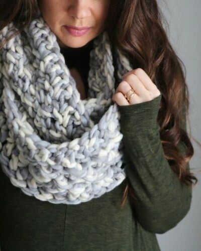 A woman wearing a grey and white knitted infinity scarf.