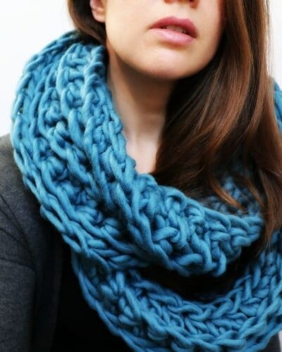 Description: A woman wearing a blue crochet infinity scarf.