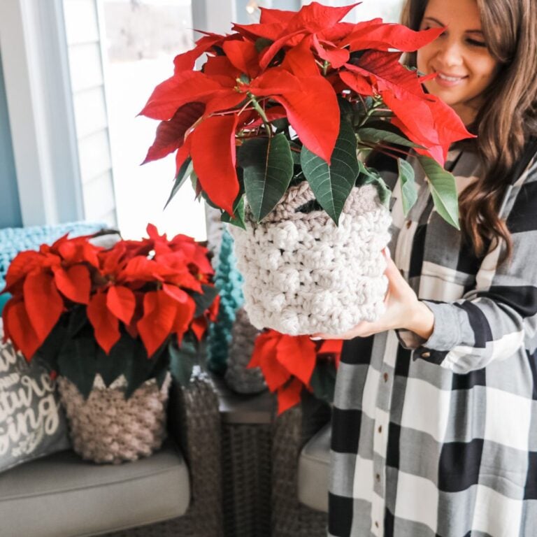A woman with a bobble stitch crochet basket holding a potted poinsettia.