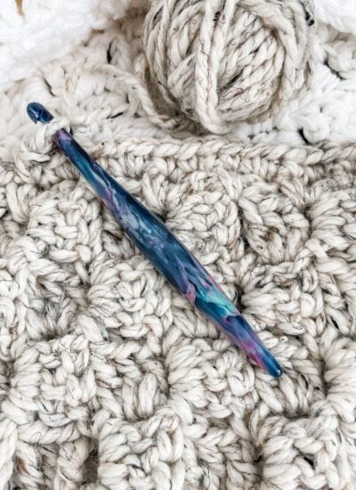 A crochet needle gracefully resting on top of a crocheted C2C blanket.