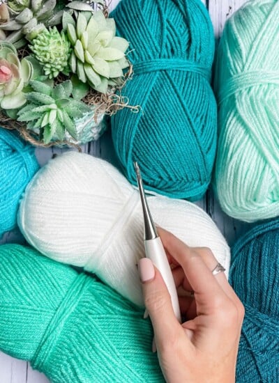 A person holding a knitting needle next to a bunch of yarn, showcasing Crochet Tips.