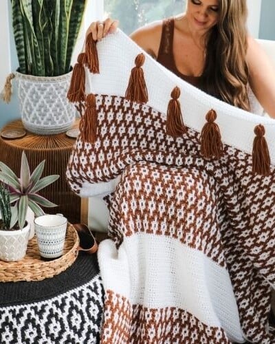 A woman holding a Desert Dunes Mosaic Blanket.