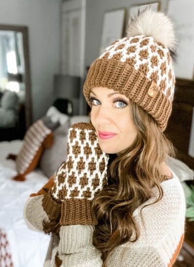 A woman wearing a brown and white knit hat and Mosaic Crochet mittens.