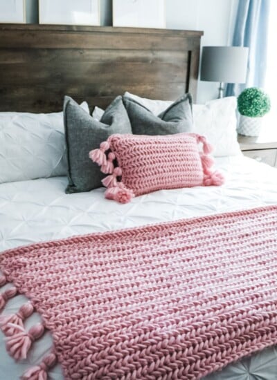 A plush bed adorned with a pink blanket and tassels.