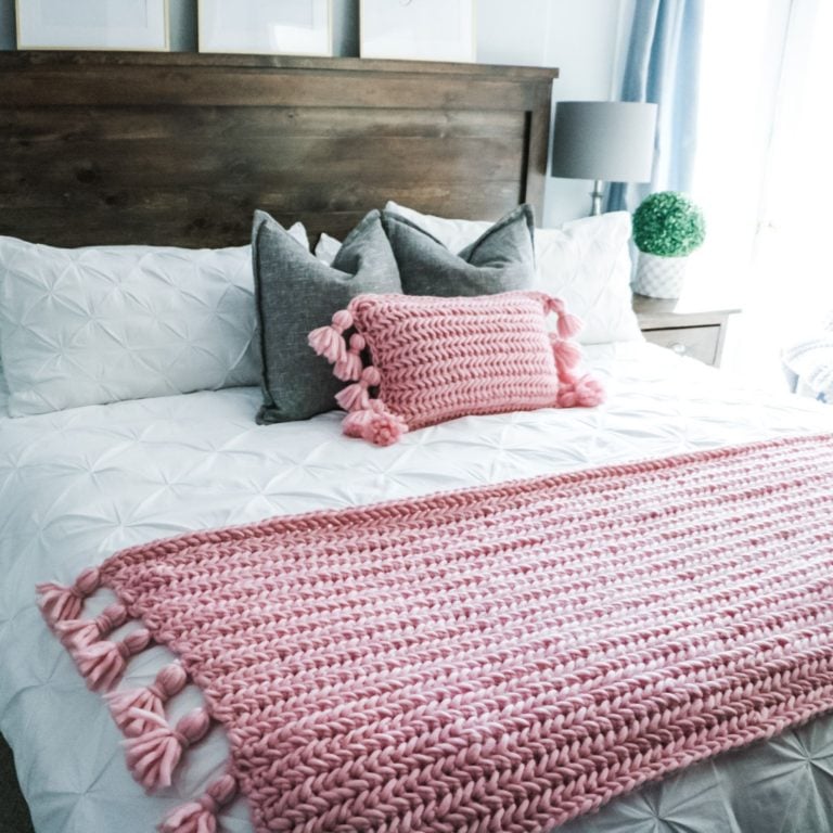 A plush bed adorned with a pink blanket and tassels.