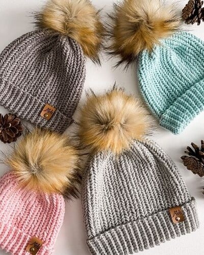Four Heavenly Herringbone hats with pom poms and pine cones.
