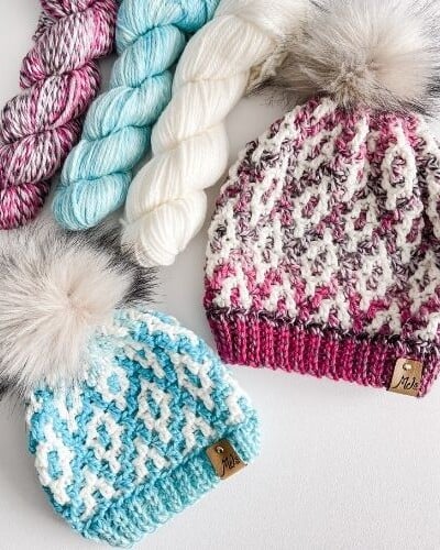 A knitted beanie with yarn and a pom pom.