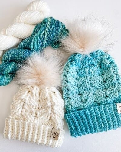 Two knitted hats with pom poms.
