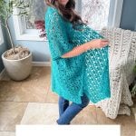 A woman poses in a blue lace kimono, known as the "Lacy Days Kimono," standing in a room with large windows, a plant, and a textured blanket on a chair. Text reads: "Crochet Pattern & Video, Sizes XS-5X.