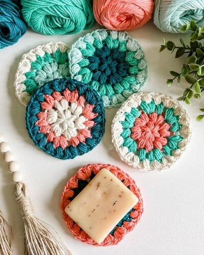 Colorful crocheted coasters with yarn and tassels.