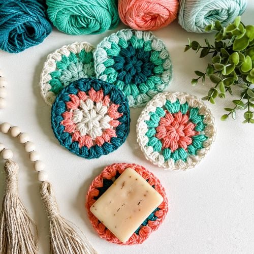 Colorful crocheted coasters with yarn and tassels.