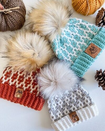 Four Hello Pumpkin crocheted hats with pom poms.
