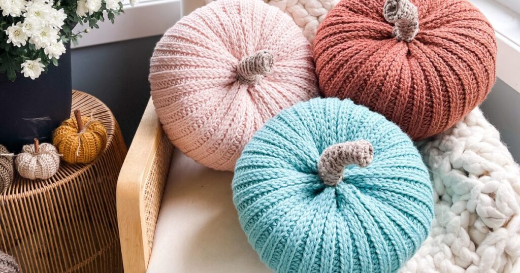Three crochet pumpkin pillows sitting on a chair.