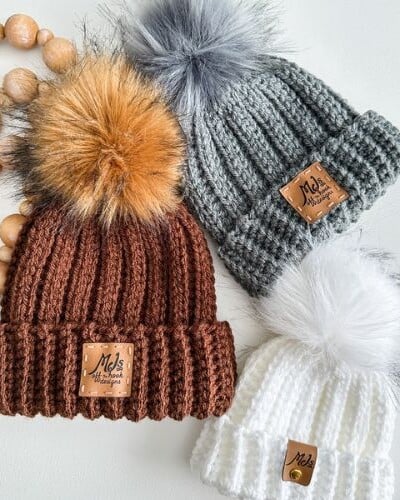 Three chunky knitted hats with pom poms.