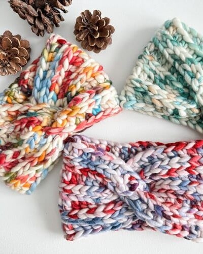 Three knitted chunky headbands with pine cones on them.