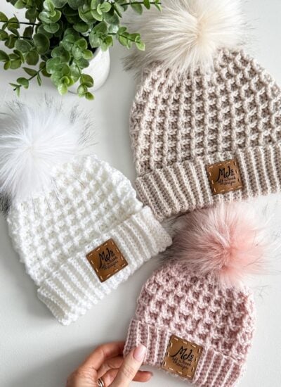 Three knitted hats with pom poms in Waffle Stitch.