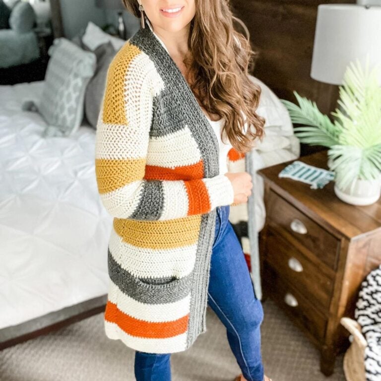 An everyday woman wearing a striped cardigan in a cozy bedroom.