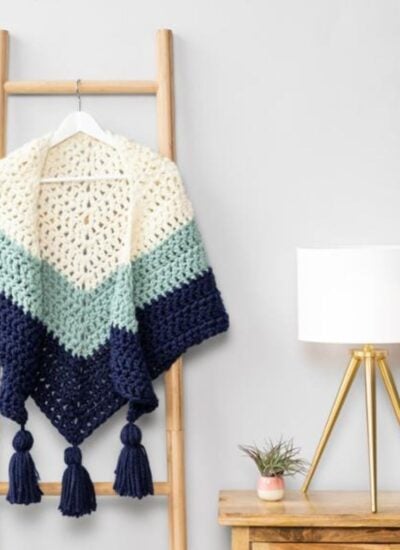 A crochet shawl draped on a ladder.