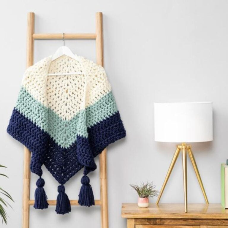 A crochet shawl draped on a ladder.