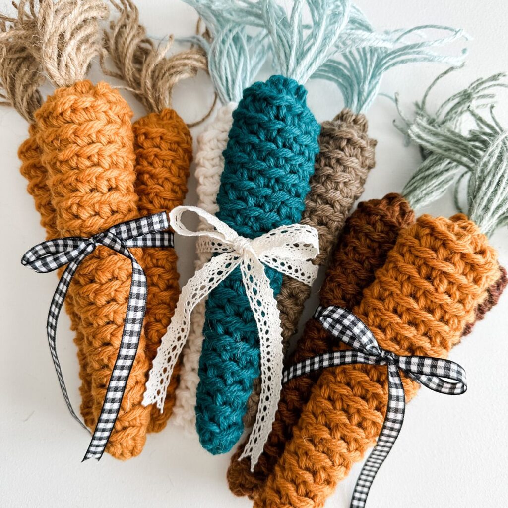 Farmhouse carrots: Four crocheted carrots with ribbons tied around them.