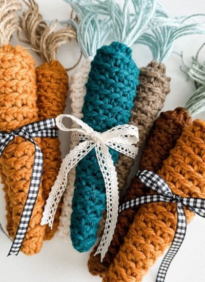 Farmhouse carrots: Four crocheted carrots with ribbons tied around them.